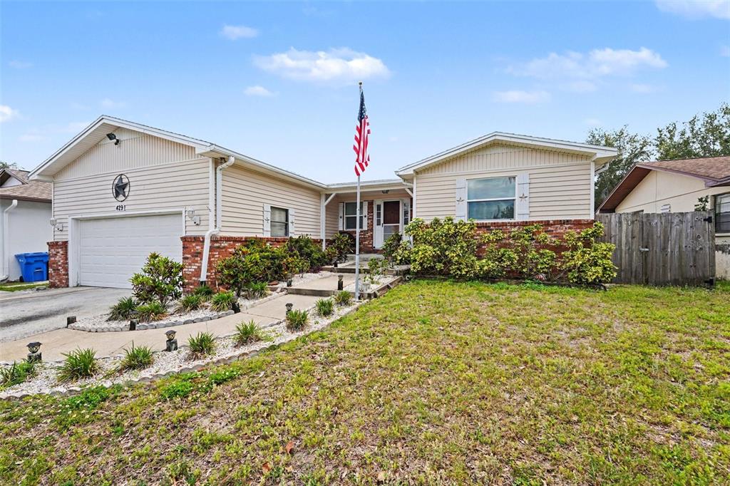 A single-story house with beige siding, a brick accent wall, and a front yard — 429 MANOR BOULEVARD, PALM HARBOR, FL