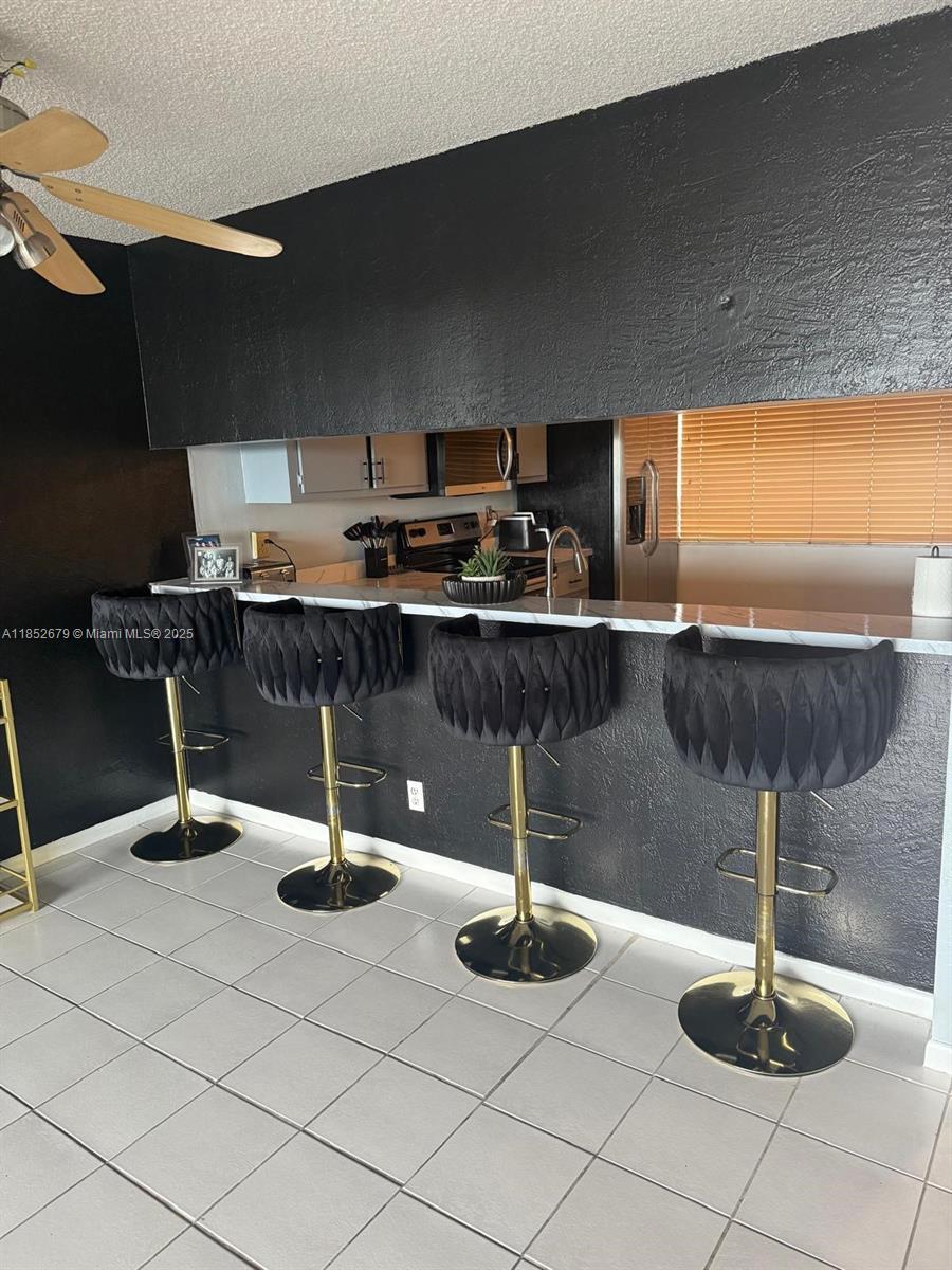 A kitchen features a breakfast bar with four black velvet stools and gold bases — 8040 Hampton Blvd # 512, North Lauderdale FL 33068, NORTH LAUDERDALE, FL