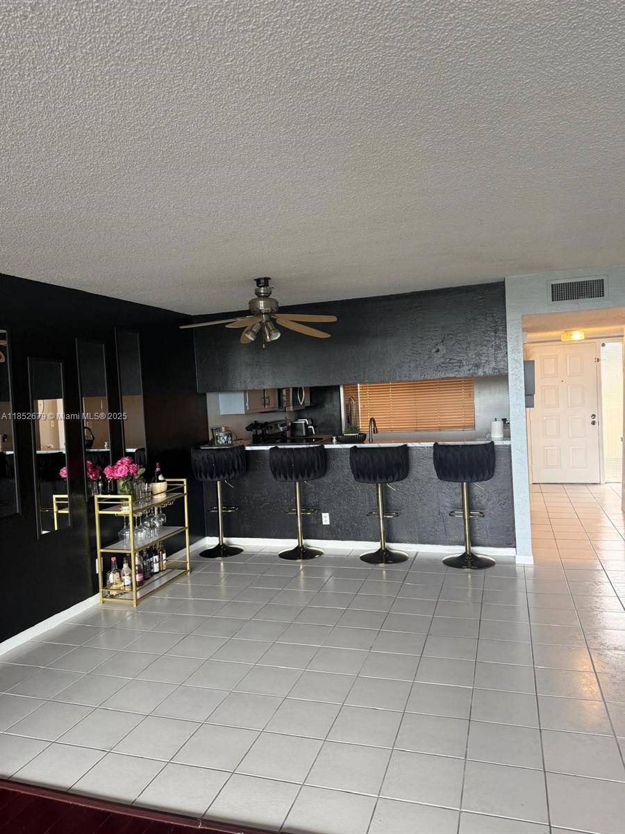 A kitchen with a black breakfast bar, four stools, and a gold bar cart — 8040 Hampton Blvd # 512, North Lauderdale FL 33068, NORTH LAUDERDALE, FL