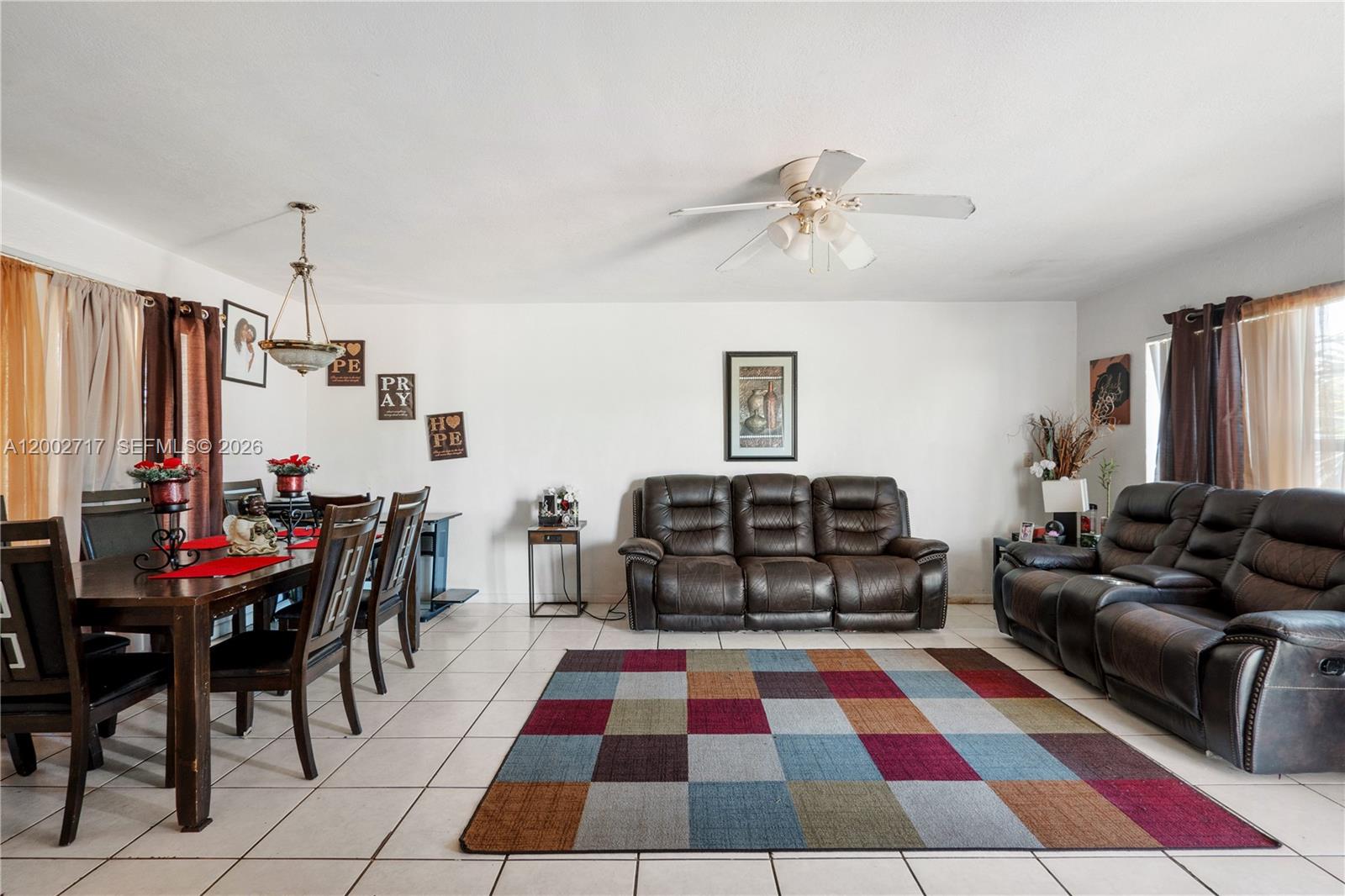 A living and dining room area with tile floors, brown leather furniture, and a colorful rug — 11960 SW 176th St, Miami FL 33177, MIAMI, FL