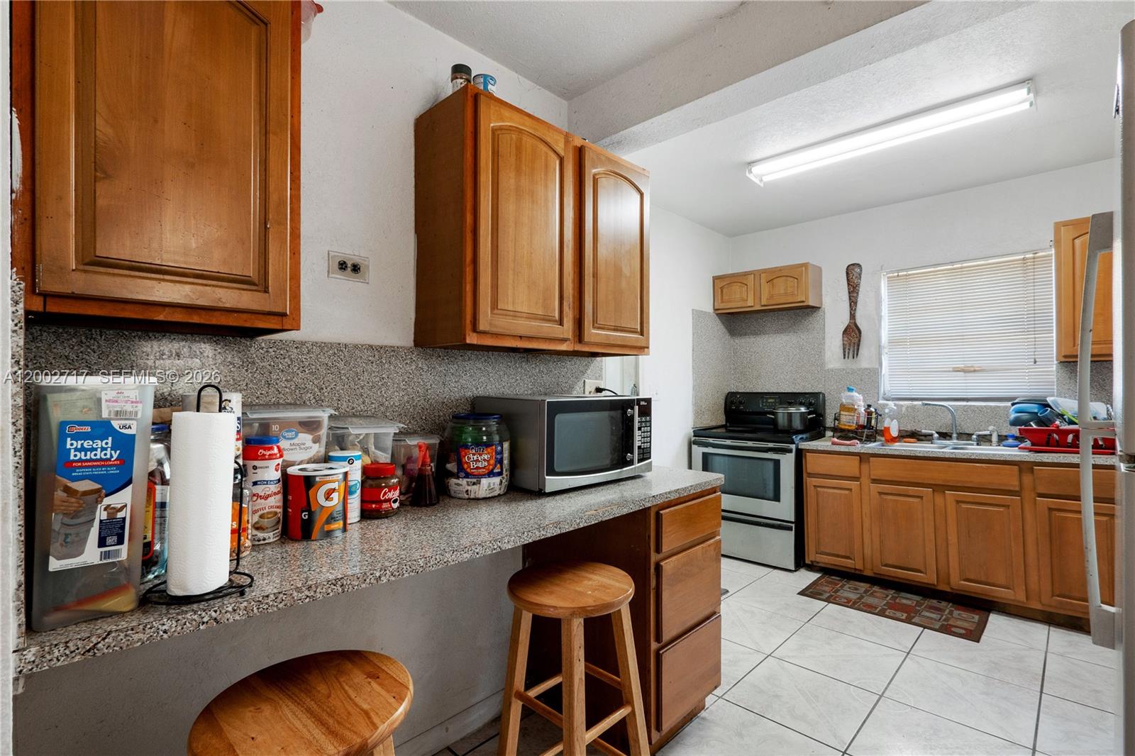 A kitchen features wood cabinets, granite countertops, a microwave, and a small breakfast bar area — 11960 SW 176th St, Miami FL 33177, MIAMI, FL
