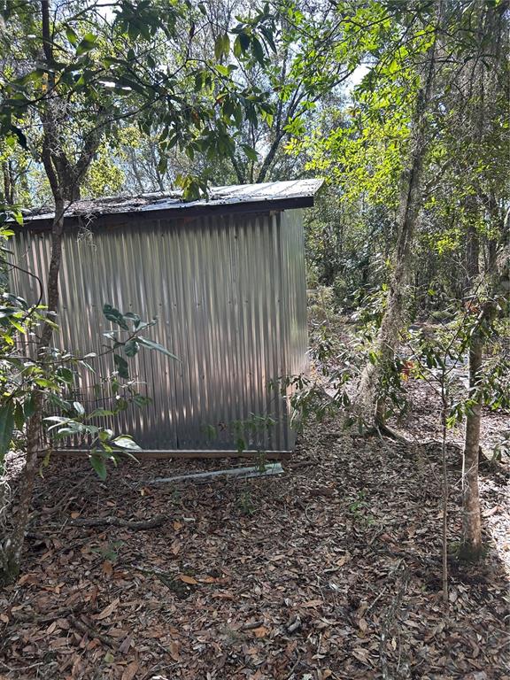 A metal storage shed sits in a wooded area covered with fallen leaves — 7740 E SMOKE TRAIL, INVERNESS, FL