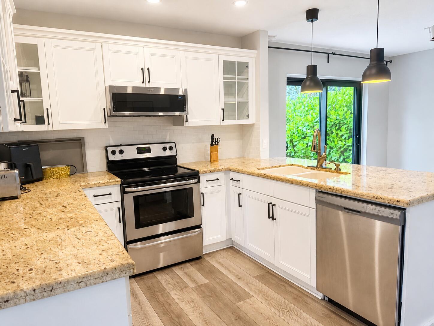 A kitchen with white cabinets, granite countertops, stainless steel appliances, and wood-look flooring — 1759 Harborside Circle, Wellington FL 33414, WELLINGTON, FL
