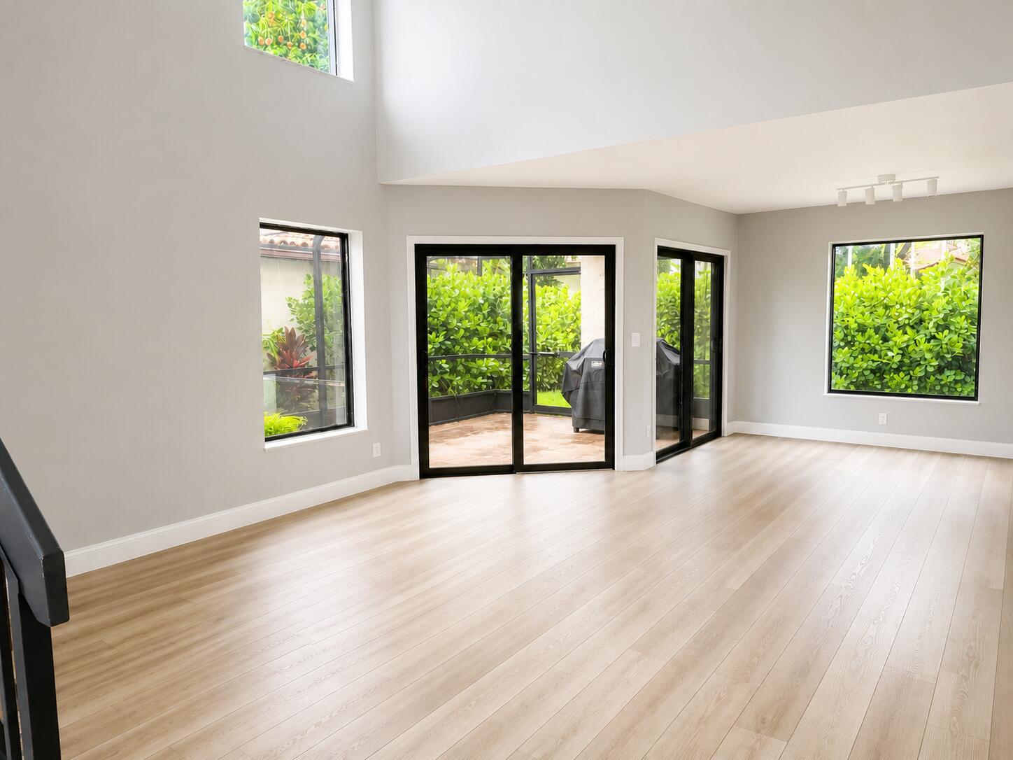A bright, empty living room features light wood flooring, tall ceilings, and large glass doors — 1759 Harborside Circle, Wellington FL 33414, WELLINGTON, FL
