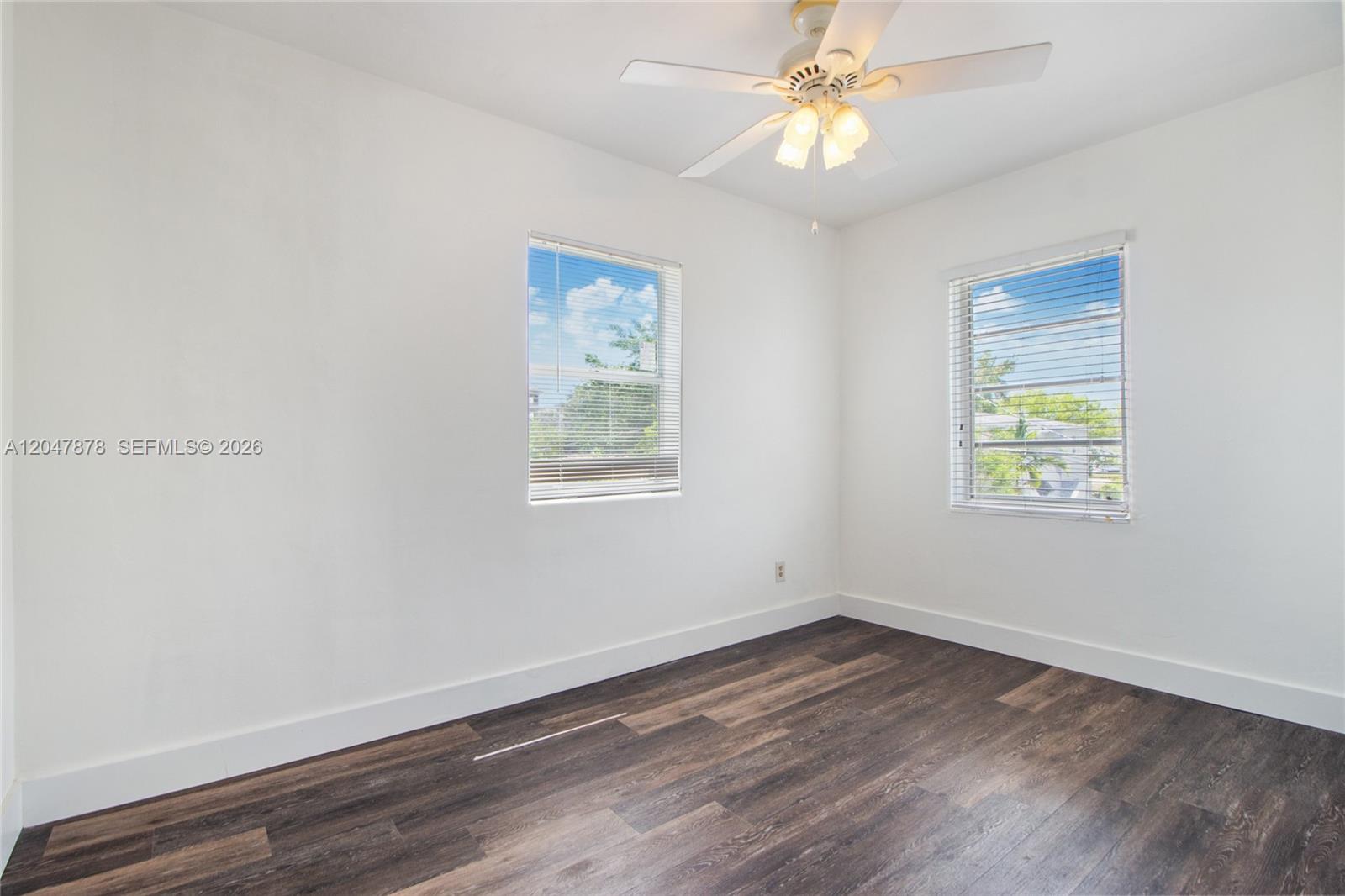 An empty bedroom features white walls, dark wood-look flooring, two windows, and a ceiling fan — 2352 SW 26th Ln, Miami FL 33133, MIAMI, FL