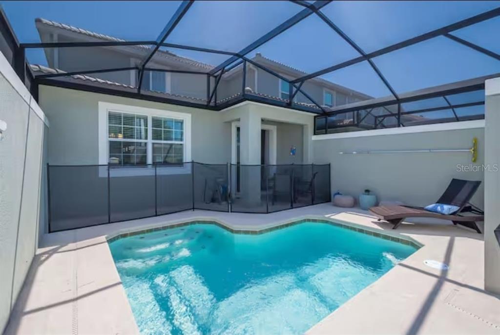 A small backyard swimming pool with a safety fence enclosed by a screened-in lanai — 4975 WINDERMERE AVENUE, KISSIMMEE, FL