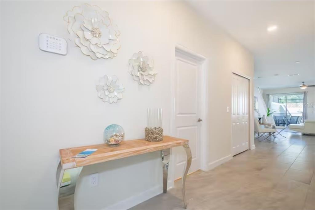 A hallway features a wooden console table, wall-mounted floral decor, and tiled flooring — 4975 WINDERMERE AVENUE, KISSIMMEE, FL