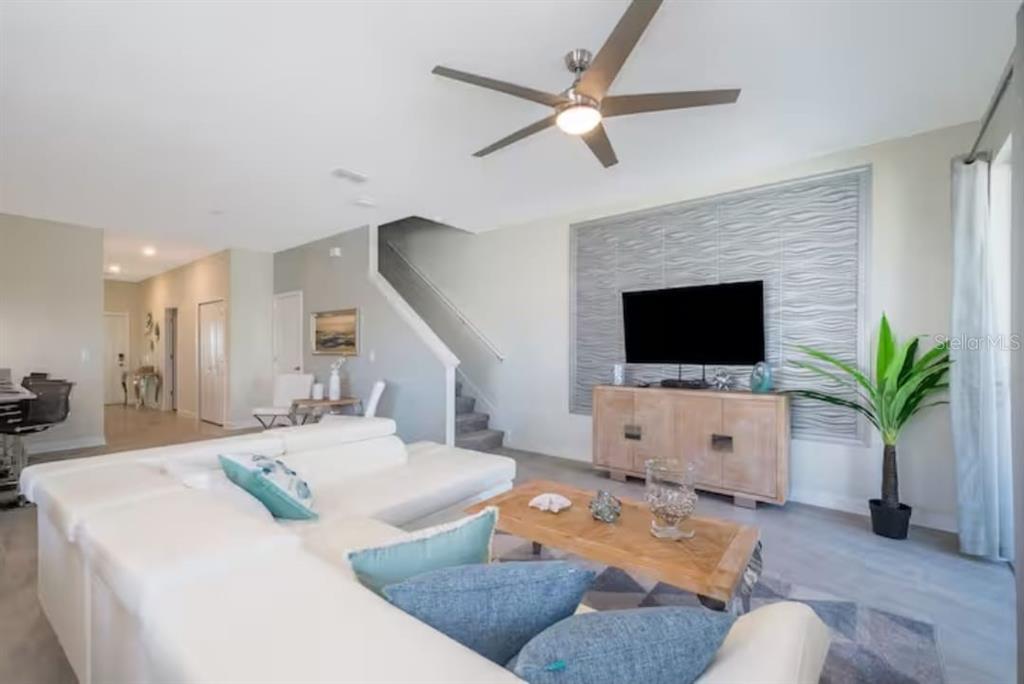 A living room features a white sectional sofa, a wooden coffee table, and a staircase — 4975 WINDERMERE AVENUE, KISSIMMEE, FL