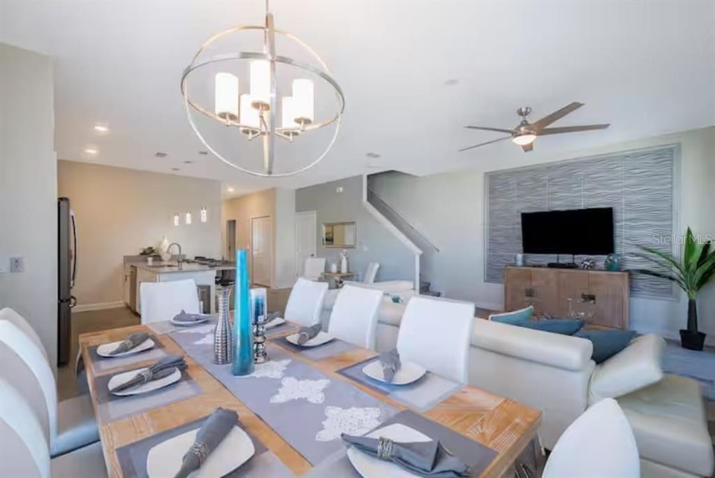 A dining area with a modern chandelier opens to a living room and kitchen — 4975 WINDERMERE AVENUE, KISSIMMEE, FL