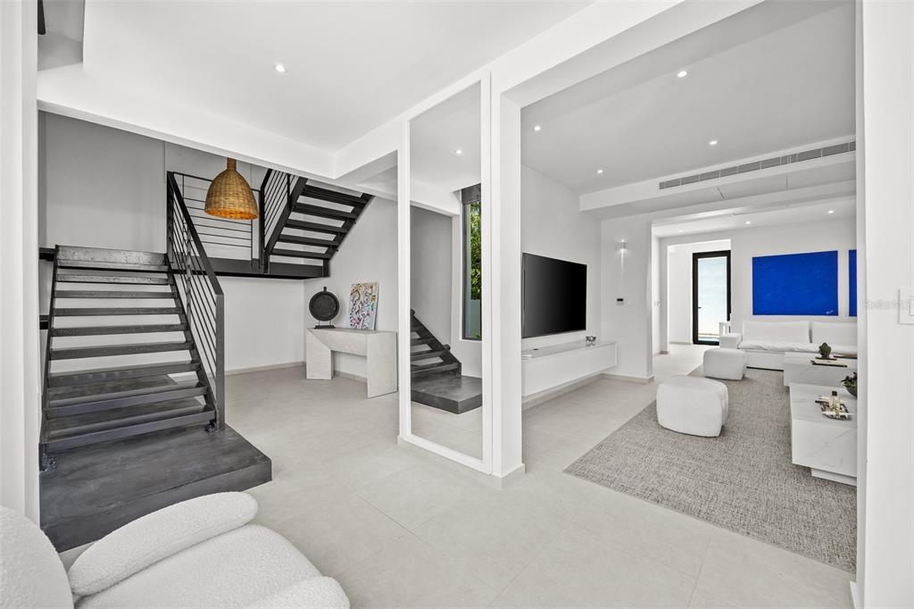A modern living room features a floating staircase, white walls, and a minimalist seating area — 66 PLACID COURT, SAN JUAN, PR