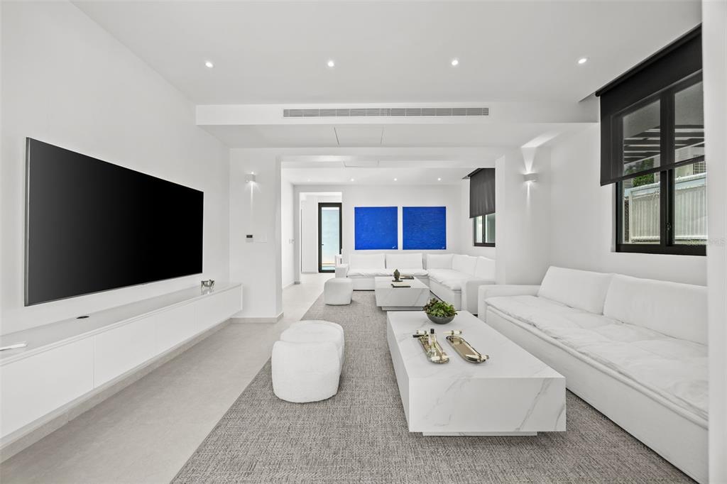 A modern, minimalist living room features white sofas, marble coffee tables, and a large television — 66 PLACID COURT, SAN JUAN, PR