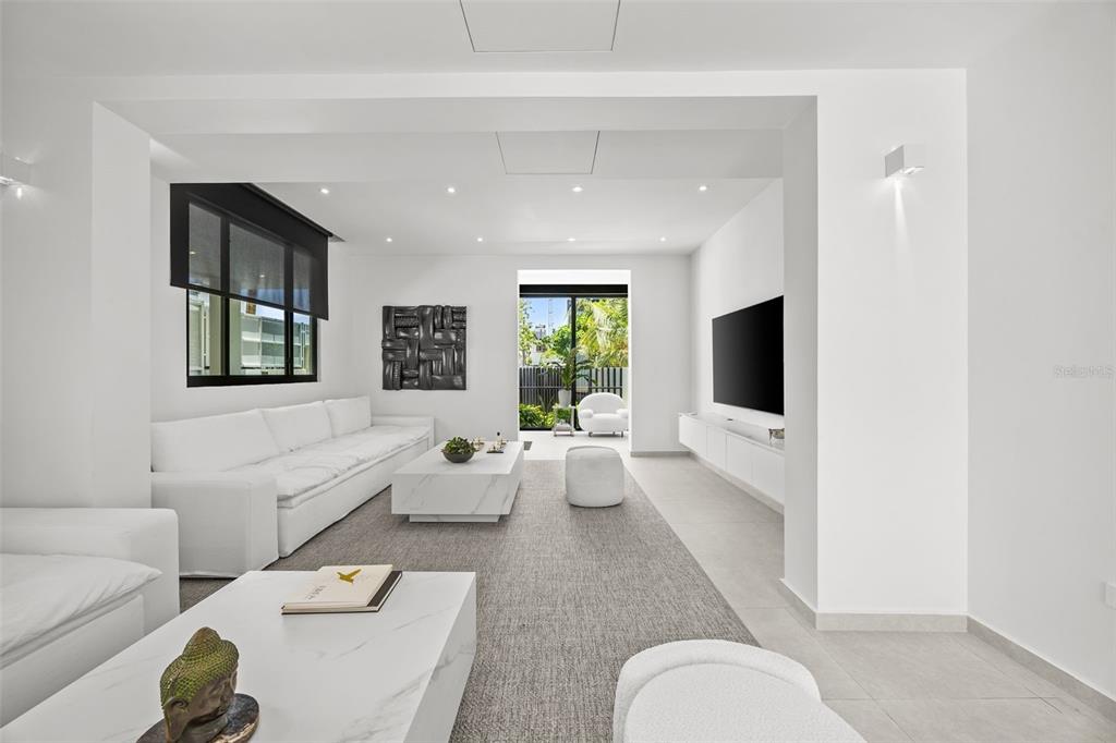 A modern, minimalist living room features white sofas, marble coffee tables, and a large television — 66 PLACID COURT, SAN JUAN, PR