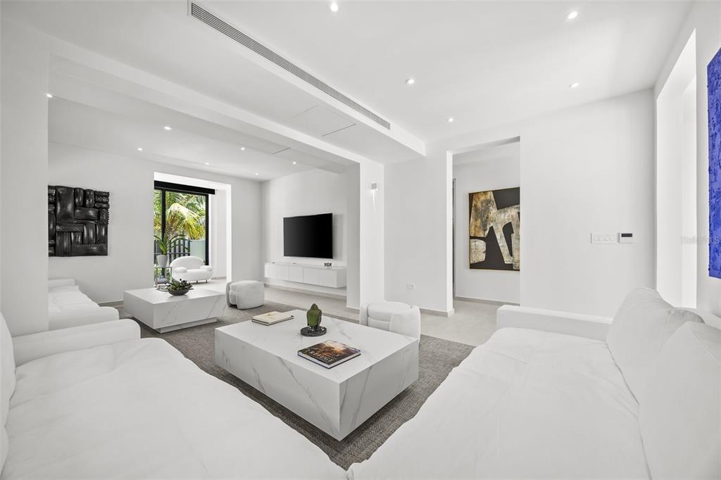 A modern, minimalist living room features white sofas, marble coffee tables, and abstract wall art — 66 PLACID COURT, SAN JUAN, PR
