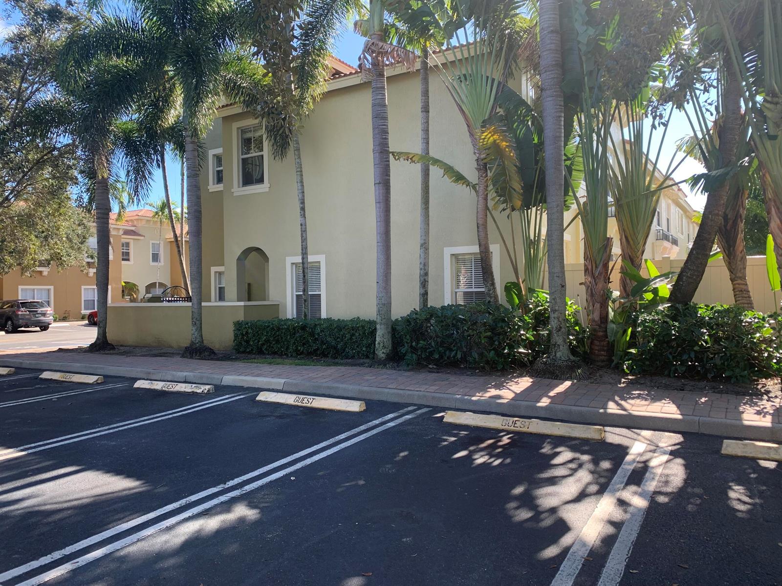 A two-story tan building with guest parking spaces in the foreground and palm trees — 101 Lake Monterey Circle, Boynton Beach FL 33426, BOYNTON BEACH, FL