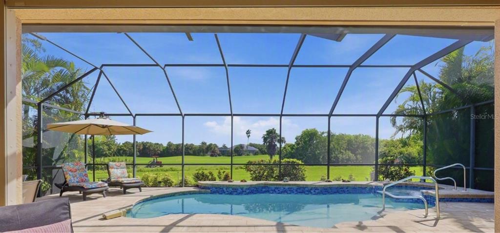 A screened-in patio features a swimming pool, lounge chairs, and a view of a golf course — 13392 GOLF POINTE DRIVE, PORT CHARLOTTE, FL