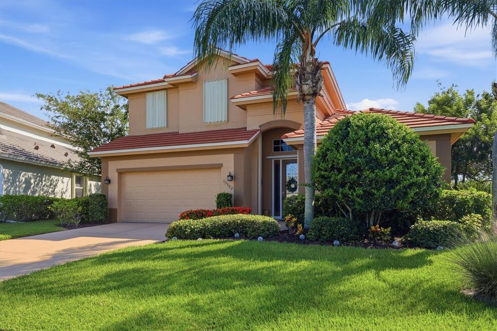 A two-story house with a tan stucco exterior, a tile roof, and a front-facing garage — 13392 GOLF POINTE DRIVE, PORT CHARLOTTE, FL