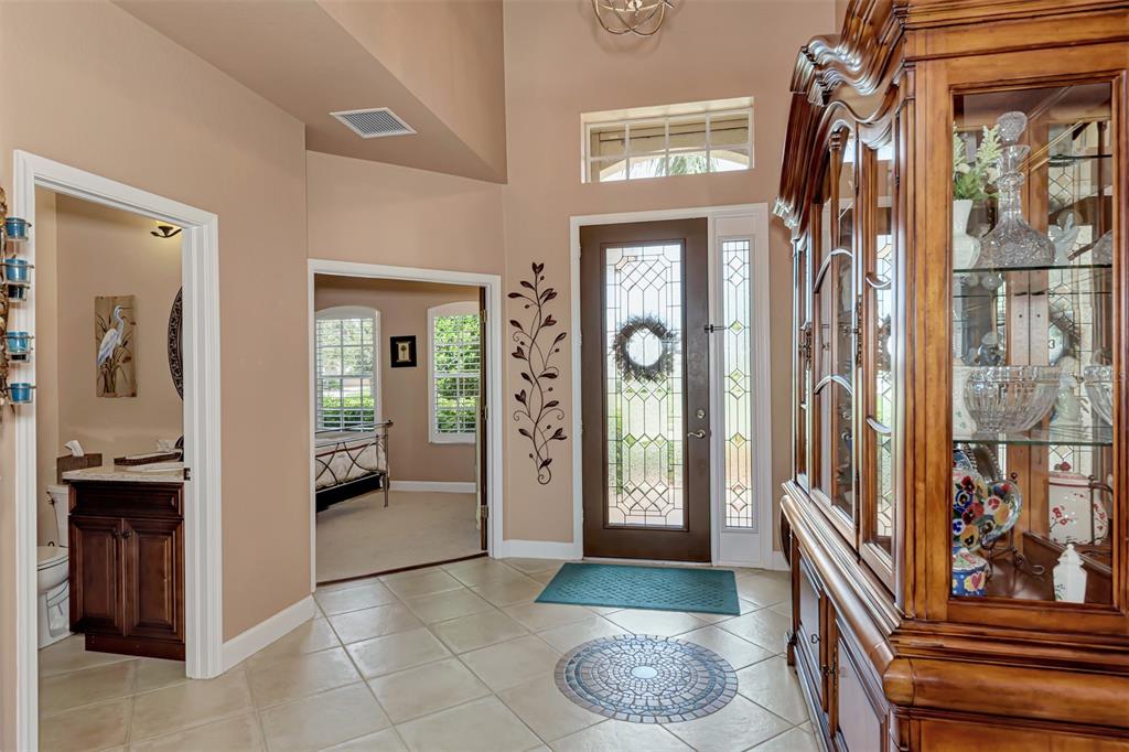 An entryway features tile flooring, a decorative glass front door, and a large wooden hutch — 13392 GOLF POINTE DRIVE, PORT CHARLOTTE, FL
