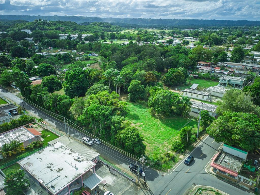 An aerial view shows a vacant grassy lot surrounded by trees and residential buildings — SR 662 SR 662 KM 1.9 SEC LOS LLANOS, ARECIBO, PR