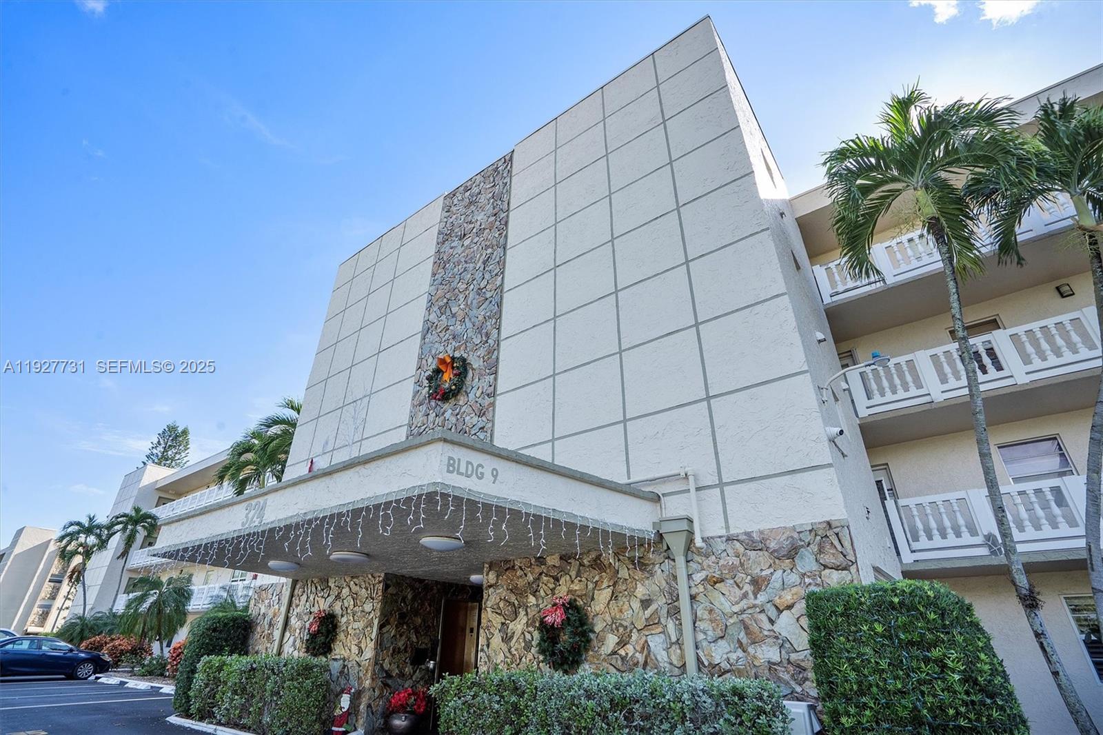 The exterior of a multi-story apartment building features stone accents and a covered entrance — 324 SE 10th St # 203, Dania Beach FL 33004, DANIA BEACH, FL