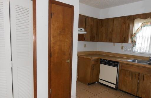 A kitchen features wood cabinets, a dishwasher, a sink, and a window with a curtain — 2007 KELLEY AVENUE, KISSIMMEE, FL