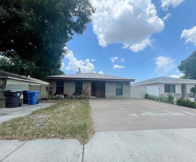 A single-story house with a metal roof and a large concrete driveway — 3804 W HAMILTON AVENUE, TAMPA, FL