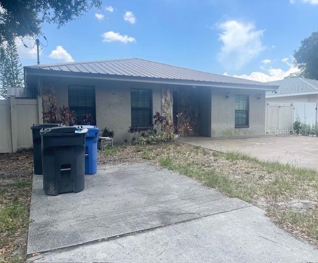 A single-story house with a metal roof, stone accents, and a concrete driveway — 3804 W HAMILTON AVENUE, TAMPA, FL