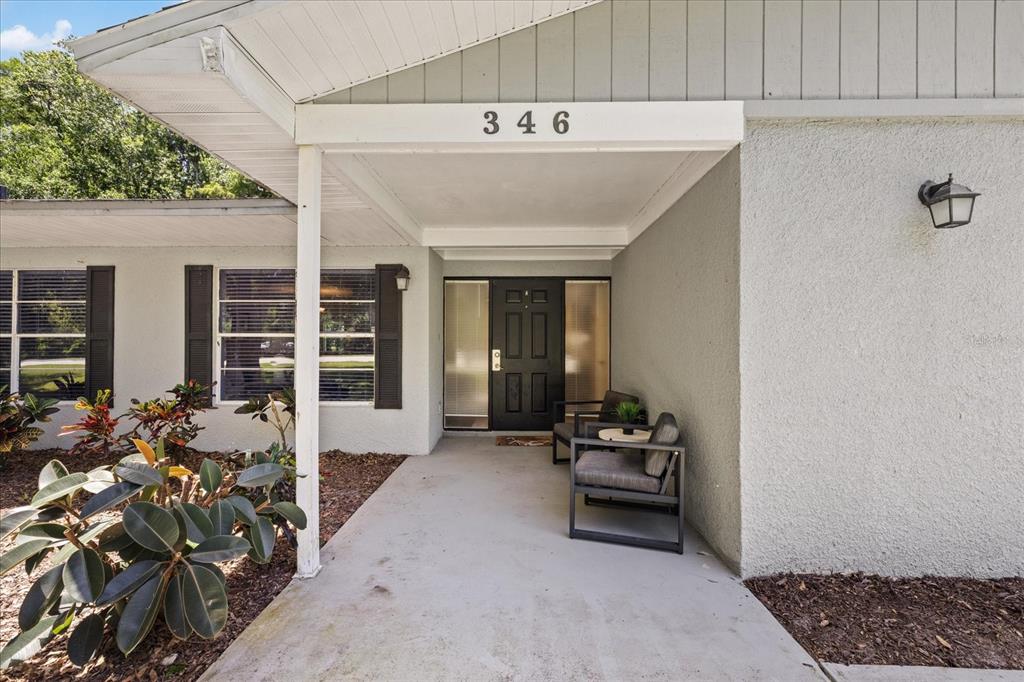 The exterior of a house features a covered entryway with a front door and chairs — 346 RANCH ROAD, TARPON SPRINGS, FL