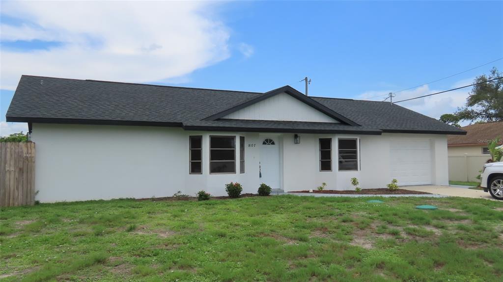A single-story white house with a dark shingled roof and an attached garage — 807 NECTAR ROAD, VENICE, FL