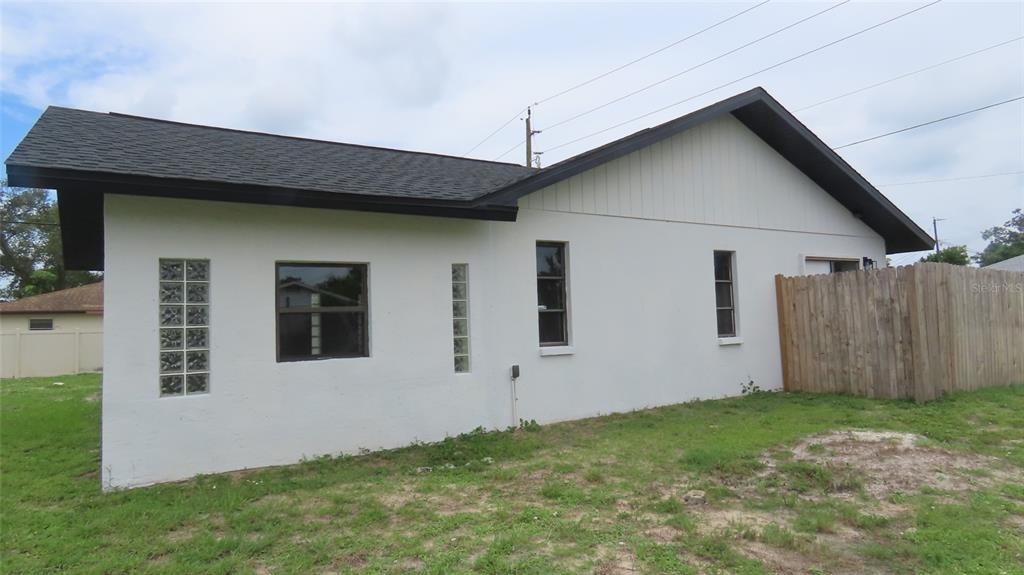 The exterior of a white, single-story house with a dark roof and glass block windows — 807 NECTAR ROAD, VENICE, FL