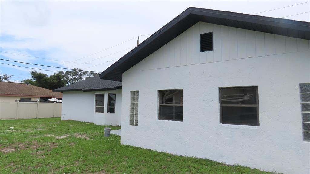 The exterior of a white stucco house features a gabled roof and glass block windows — 807 NECTAR ROAD, VENICE, FL