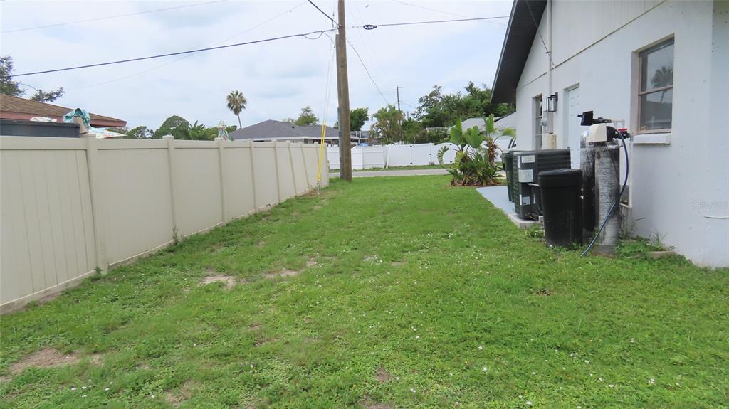A side yard features a white vinyl fence, a patch of grass, and exterior utility equipment — 807 NECTAR ROAD, VENICE, FL