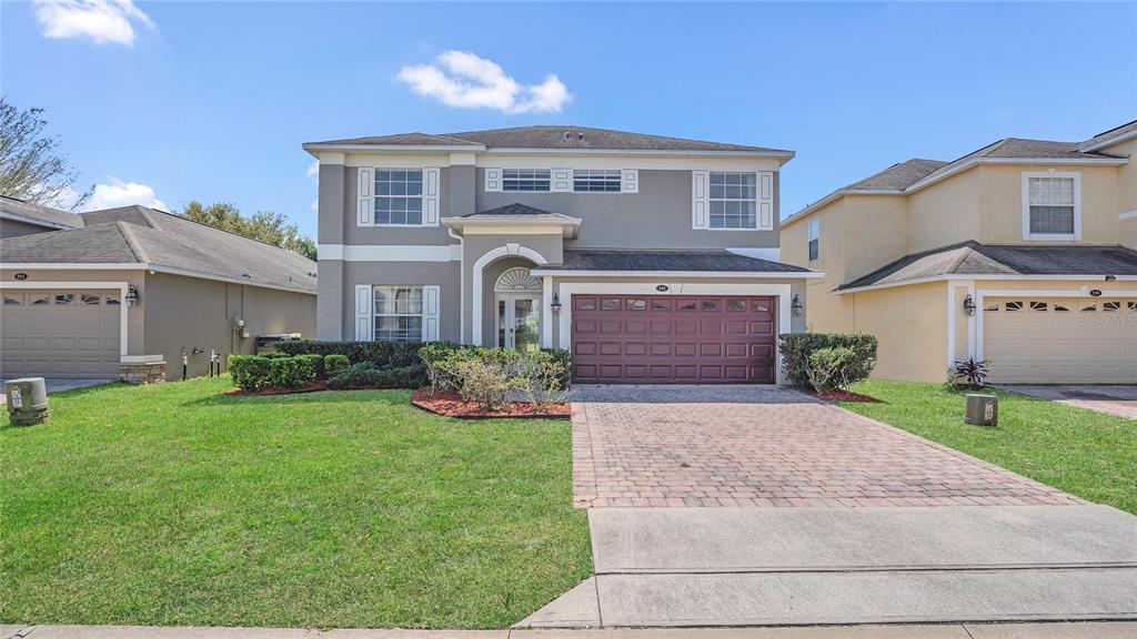 A two-story suburban house with a gray exterior, a brick driveway, and a two-car garage — 545 FAIRHAVEN DRIVE, DAVENPORT, FL