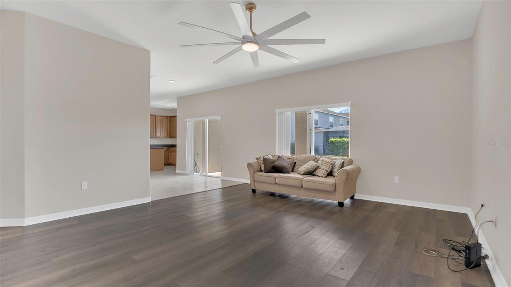 A living room with dark wood flooring, a beige sofa, and a ceiling fan — 545 FAIRHAVEN DRIVE, DAVENPORT, FL