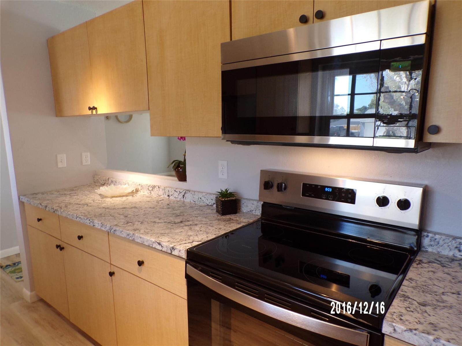 A kitchen features light wood cabinets, granite countertops, and stainless steel appliances — 2265 14th Avenue SW, Vero Beach FL 32962, VERO BEACH, FL
