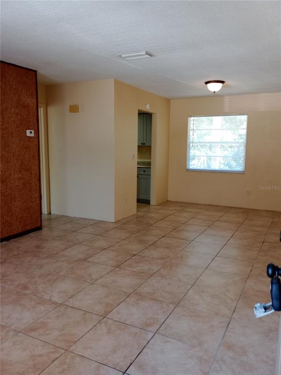 An interior view shows a living area with tiled floors leading to a kitchen doorway — 1217 KENNEDY ROAD UNIT 58, DAYTONA BEACH, FL
