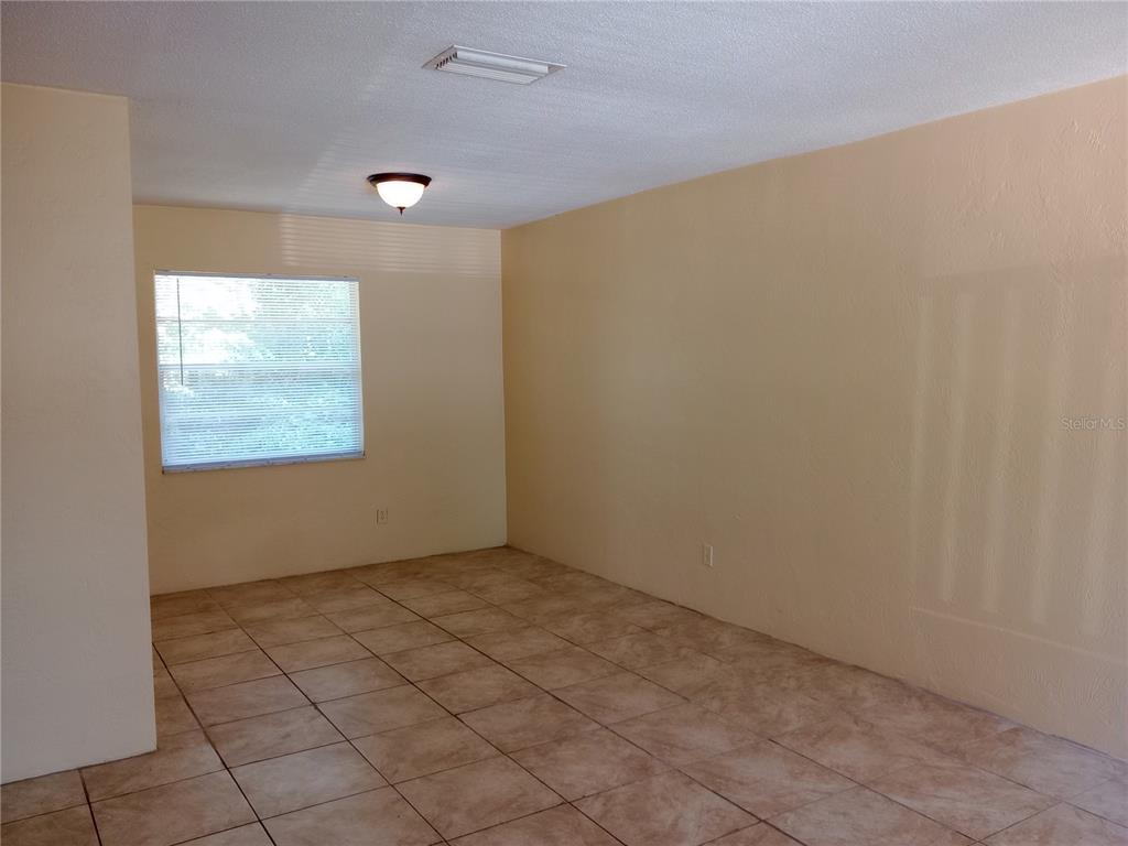 An empty room with beige walls, tile flooring, a single window, and a ceiling light — 1217 KENNEDY ROAD UNIT 58, DAYTONA BEACH, FL