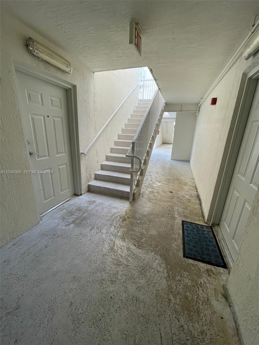 An outdoor concrete stairwell connects two levels between white apartment doors — 630 85th St # 102, Miami Beach FL 33141, MIAMI BEACH, FL