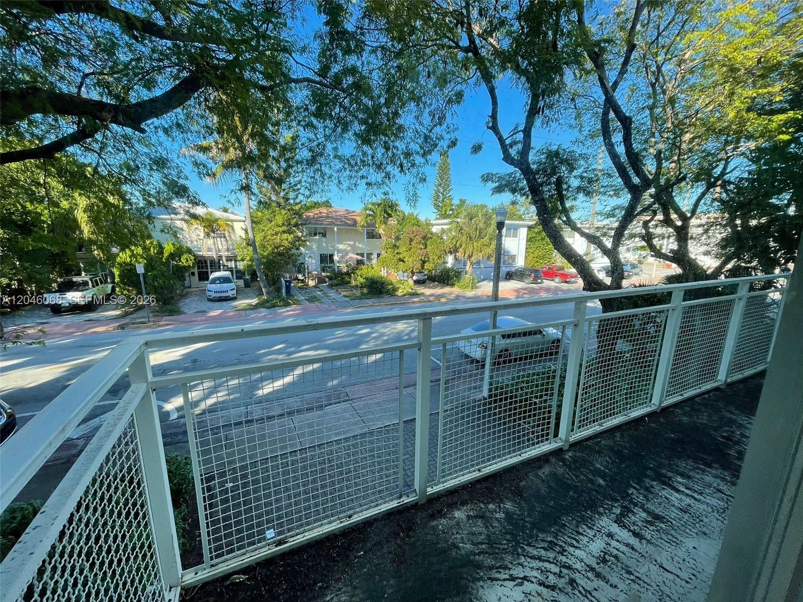 A view of a street and neighboring buildings from a balcony with metal railings — 630 85th St # 102, Miami Beach FL 33141, MIAMI BEACH, FL