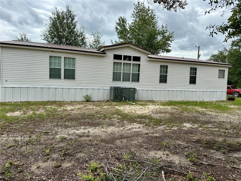 A single-story manufactured home with white siding and a metal roof sits on a lot — 9889 NW 9TH COURT, BRANFORD, FL