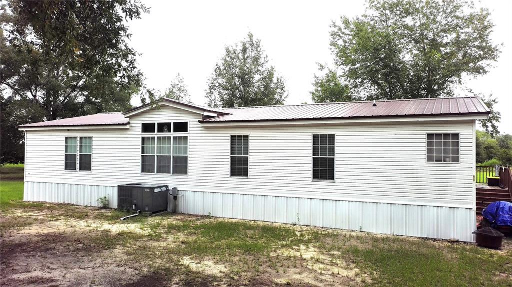 The exterior of a single-story manufactured home features white siding and a metal roof — 9889 NW 9TH COURT, BRANFORD, FL