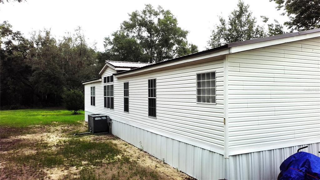 A side view of a white mobile home with vinyl siding and a metal roof — 9889 NW 9TH COURT, BRANFORD, FL