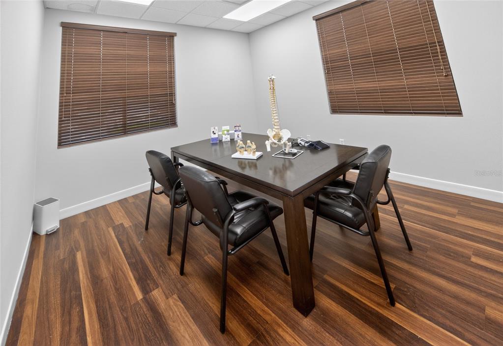 A medical consultation room features a dark wood table, chairs, and anatomical models — 4064 E STATE ROAD 44, WILDWOOD, FL