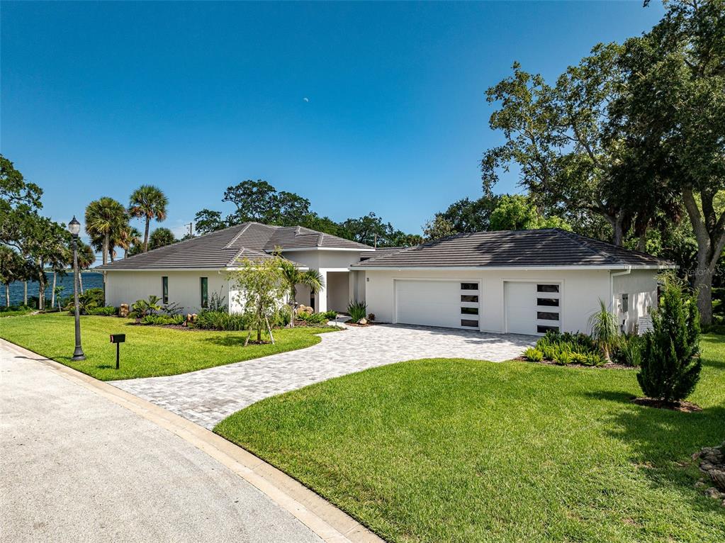A modern white house with a tiled roof and a paved driveway sits on grass — 11 BAYSHORE COURT, ROCKLEDGE, FL