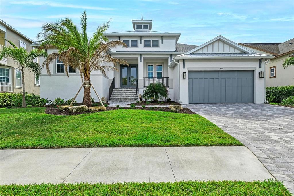 A modern two-story house features a gray garage, a palm tree, and a front entrance — 8211 37TH AVENUE CIRCLE W, BRADENTON, FL