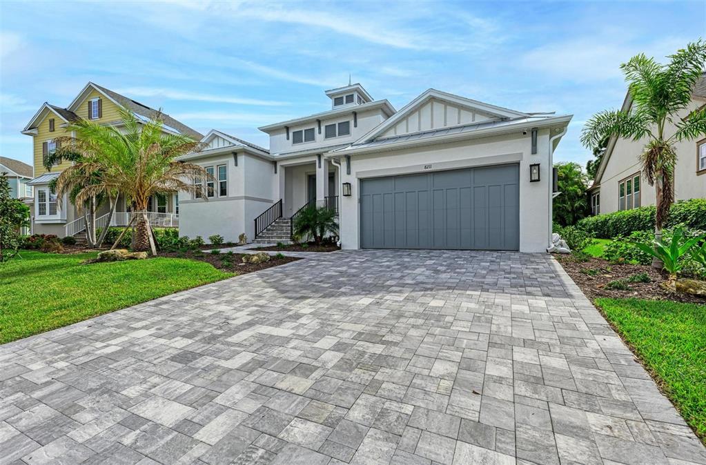 A modern single-story house with a gray garage door and a paved driveway — 8211 37TH AVENUE CIRCLE W, BRADENTON, FL