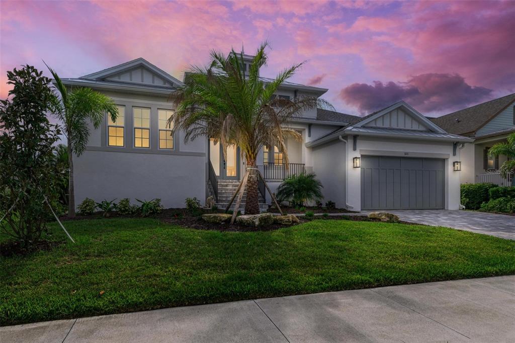 A modern two-story house features a gray garage, a palm tree, and a sunset sky — 8211 37TH AVENUE CIRCLE W, BRADENTON, FL