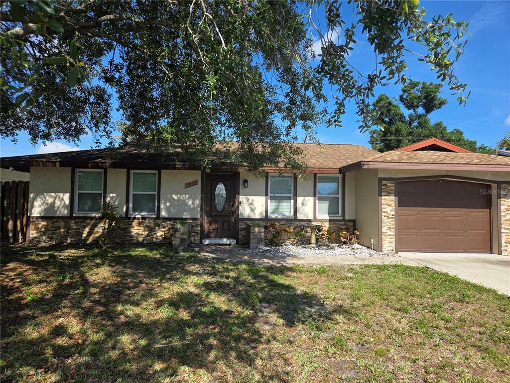 A single-story house with a brown garage door, stone accents, and a large tree in front — 3922 COCHISE TER,, SARASOTA, FL