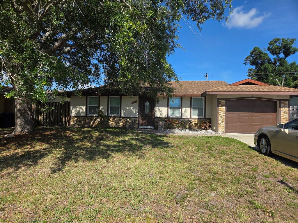 A single-story house with a brown garage door, stone accents, and a large front tree — 3922 COCHISE TER,, SARASOTA, FL