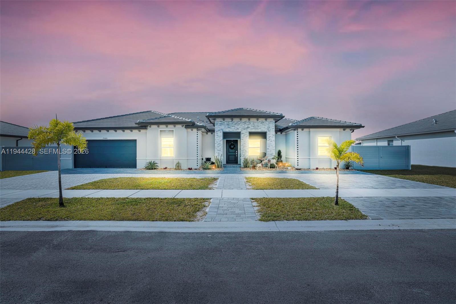A single-story house with a stone-accented entryway, a dark garage, and a paved driveway — 19080 SW 133RD CT, Miami FL 33177, MIAMI, FL