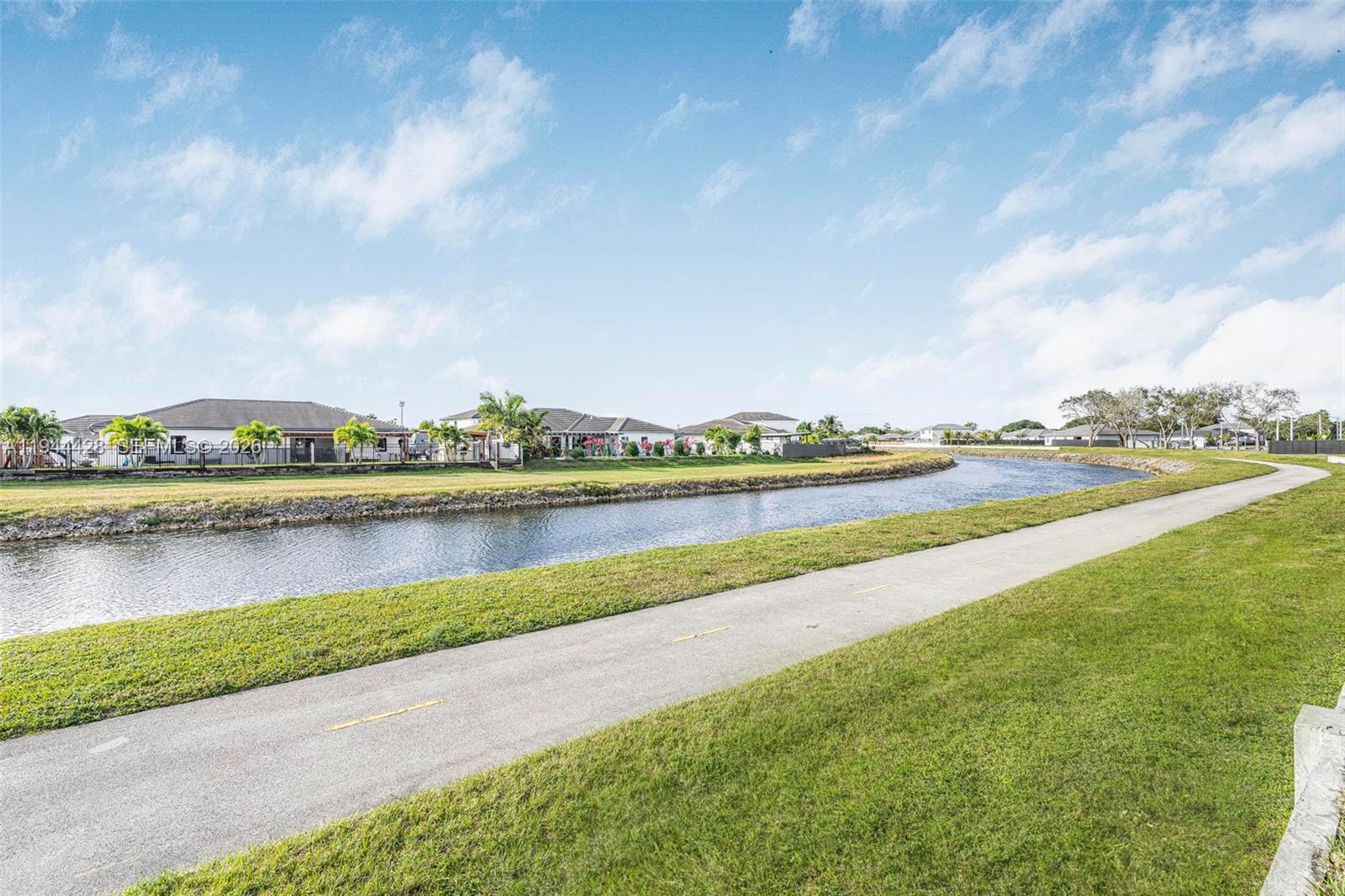 A paved walking path runs alongside a canal in front of a residential neighborhood — 19080 SW 133RD CT, Miami FL 33177, MIAMI, FL